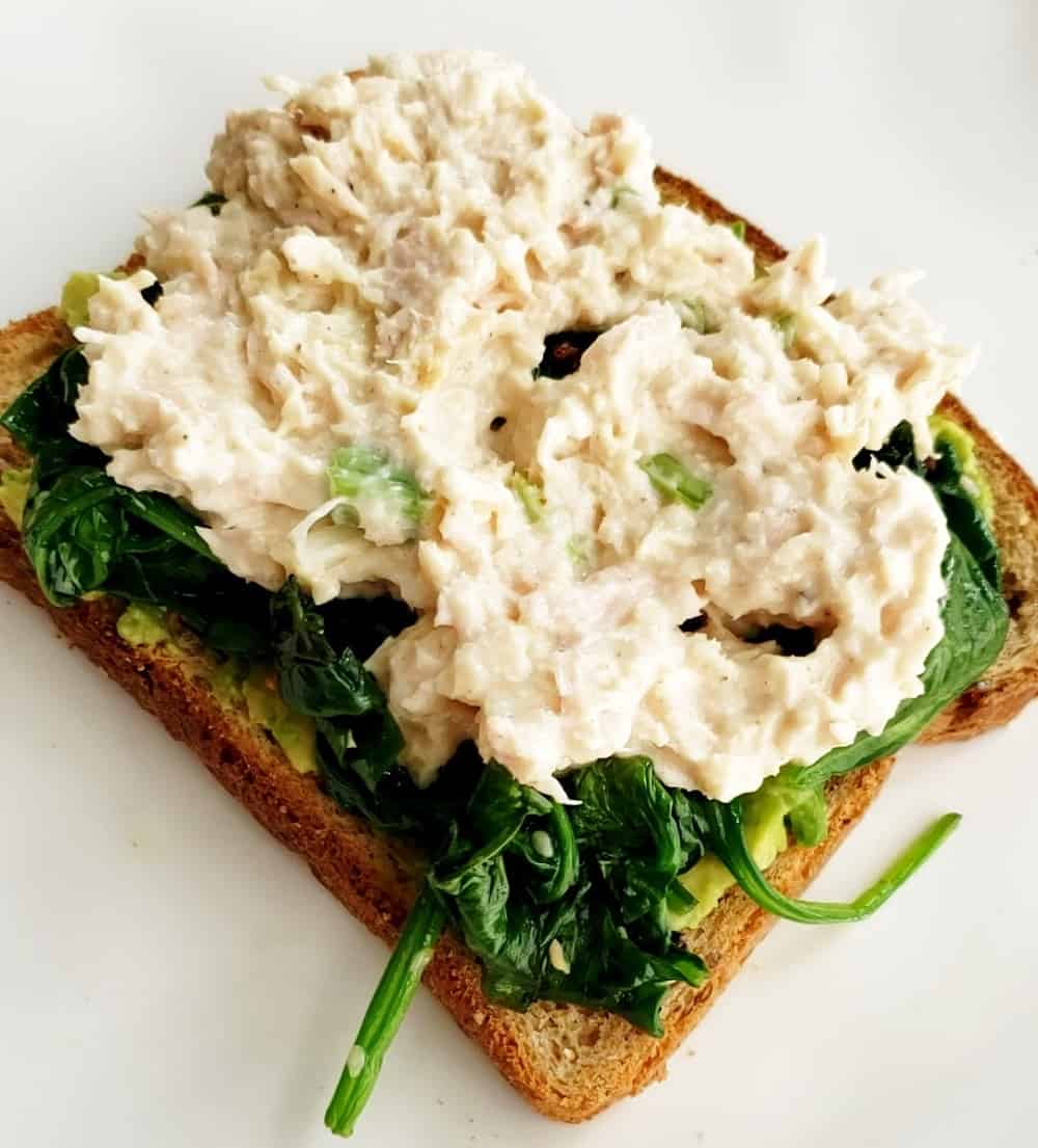 Avocado toast topped with spinach and tuna.