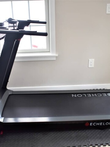 The Echelon Stride treadmill on a heavy duty foam mat, set up in a living room.
