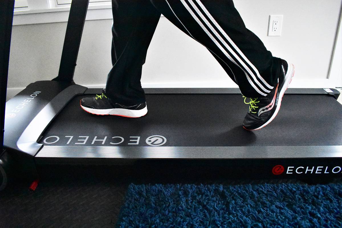 A mans feet walking on a treadmill.