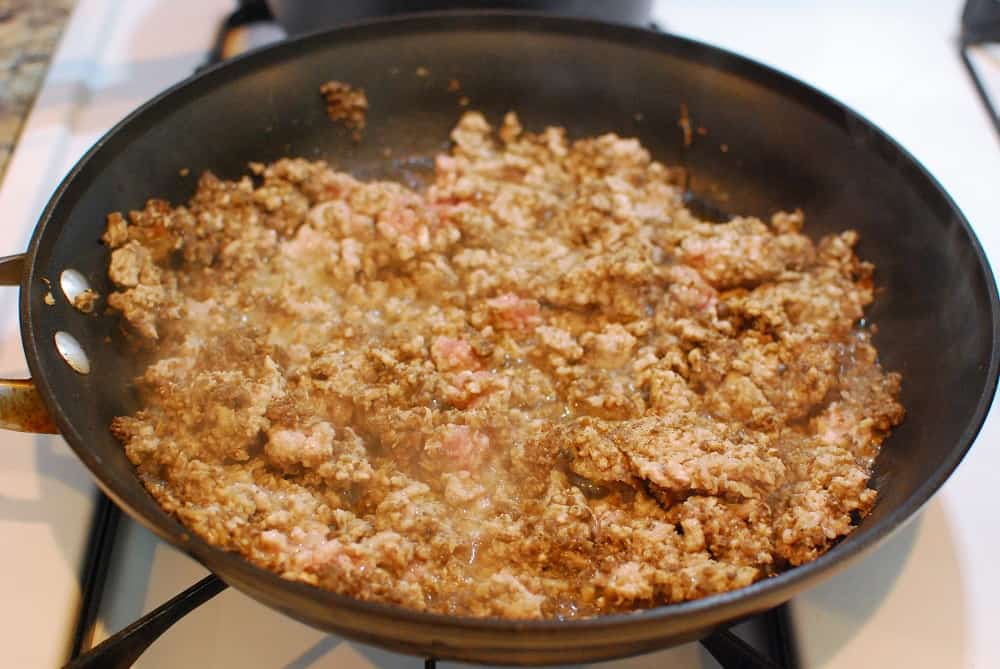 Ground pork and mushrooms cooking in a skillet.