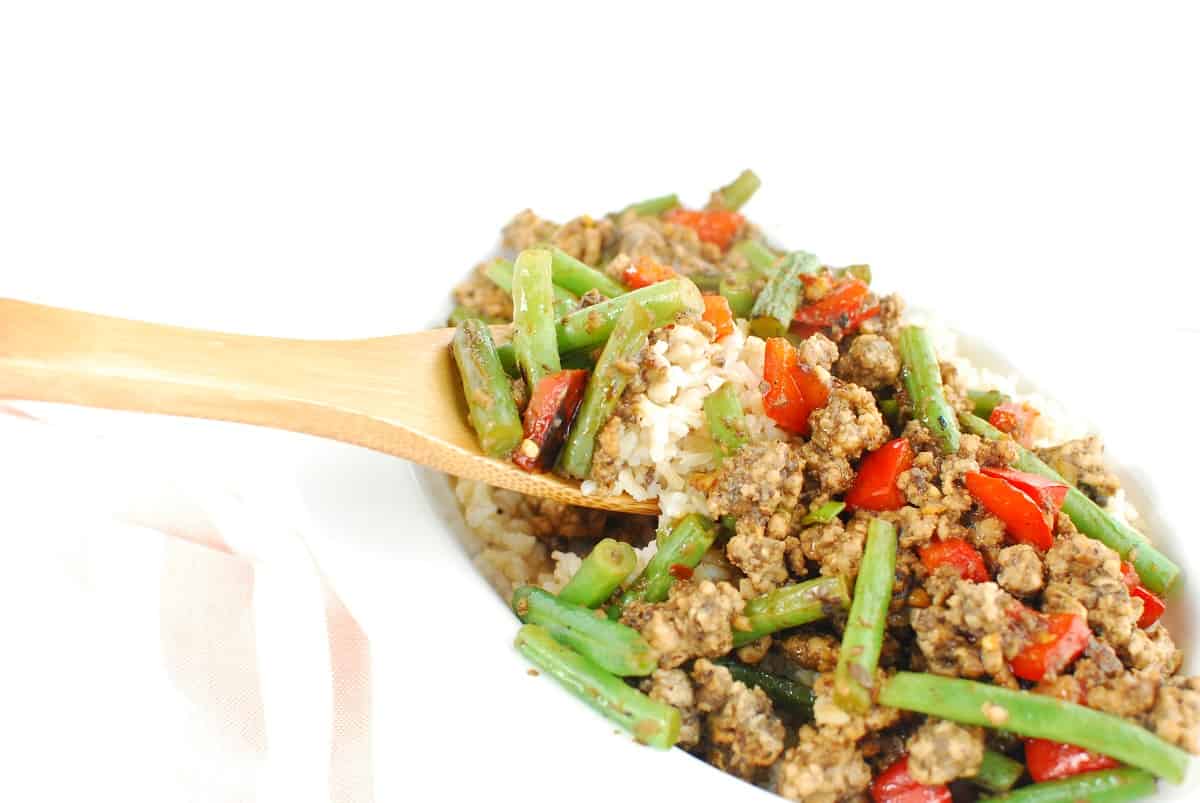 A wooden spoonful of ground pork stir fry and rice.