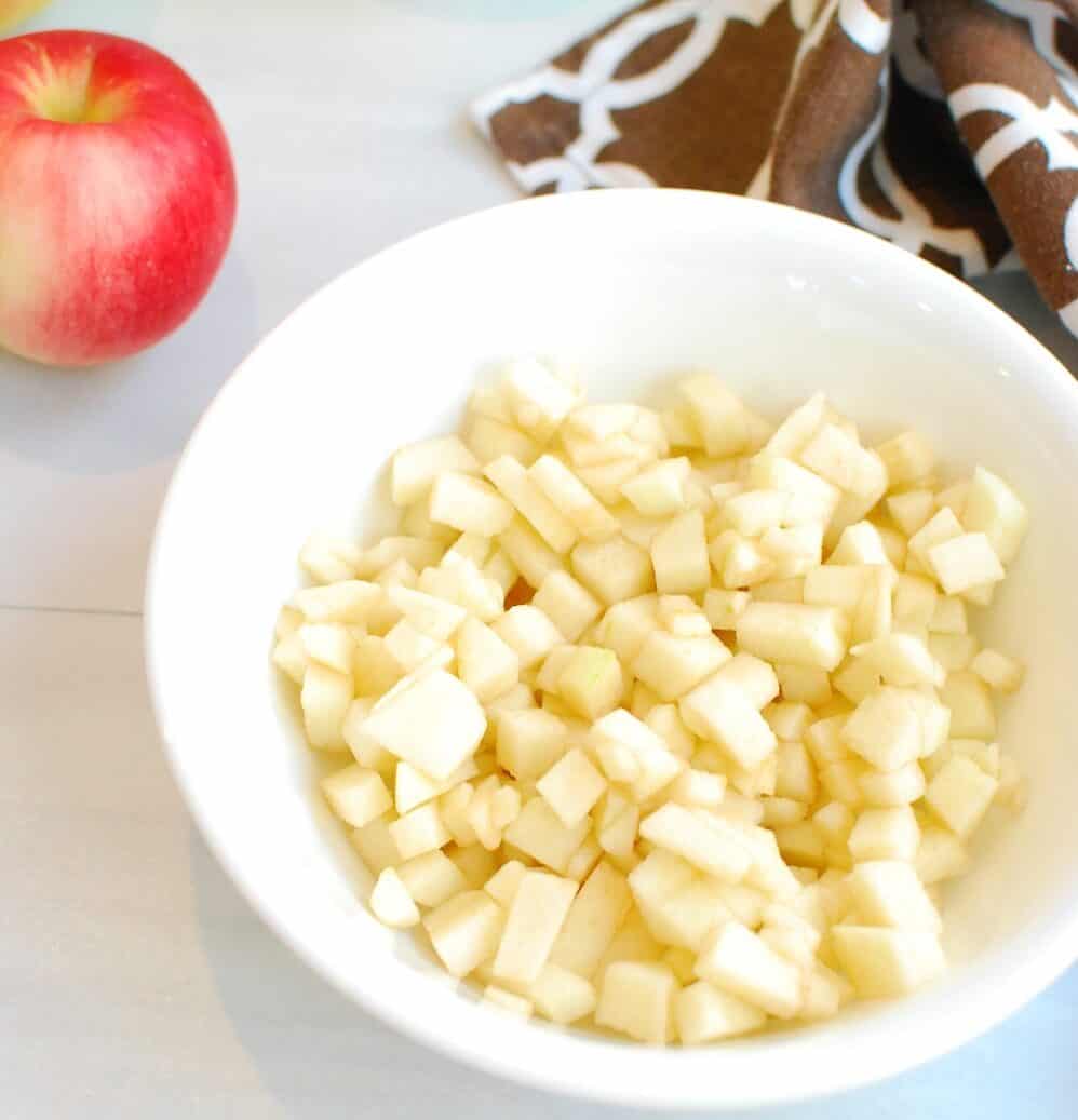 Finely chopped apples in a white bowl.