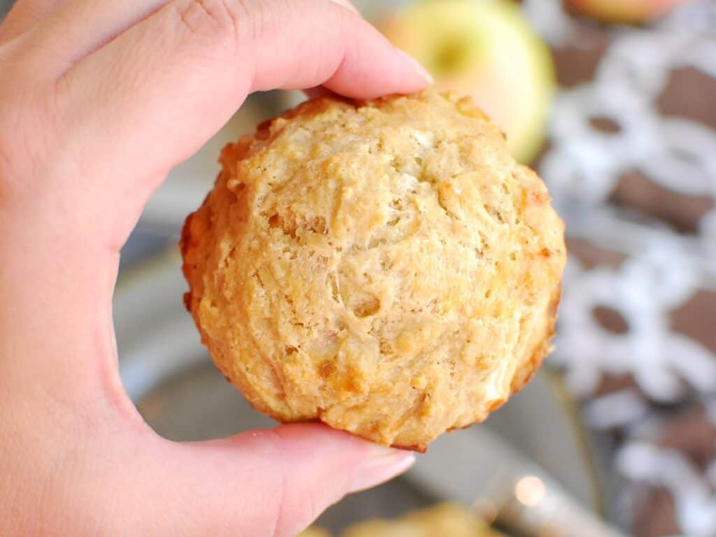 A woman's hand holding an apple cheddar muffin.