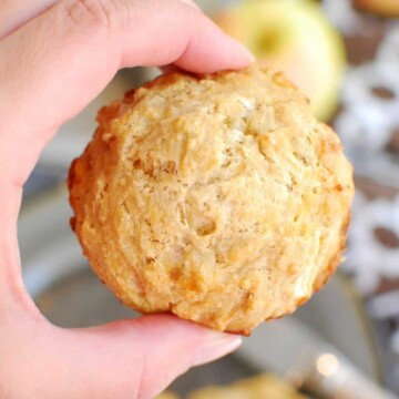 A woman's hand holding an apple cheddar muffin.