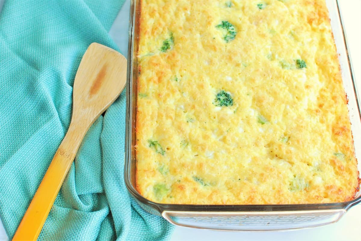 Cooked breakfast casserole in a glass baking dish next to a wooden serving utensil.