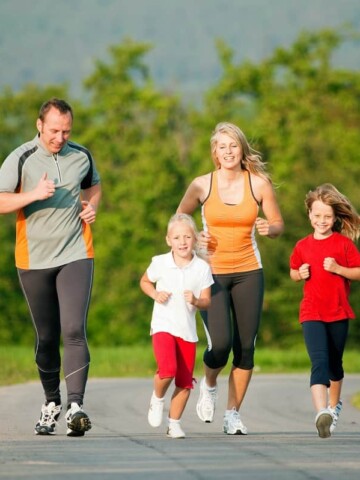 A family with kids outside running on a paved path.