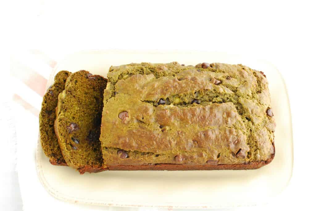 A loaf of matcha banana bread with two slices cut from the left side.