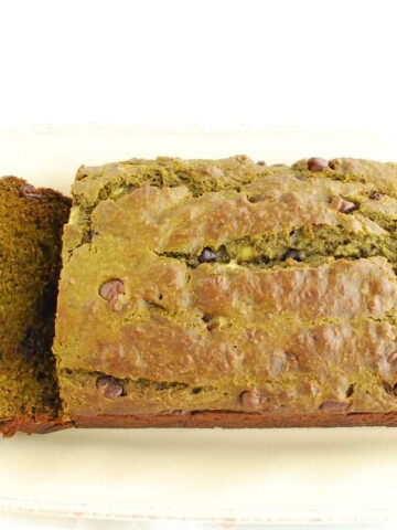 A loaf of matcha banana bread with two slices cut from the left side.