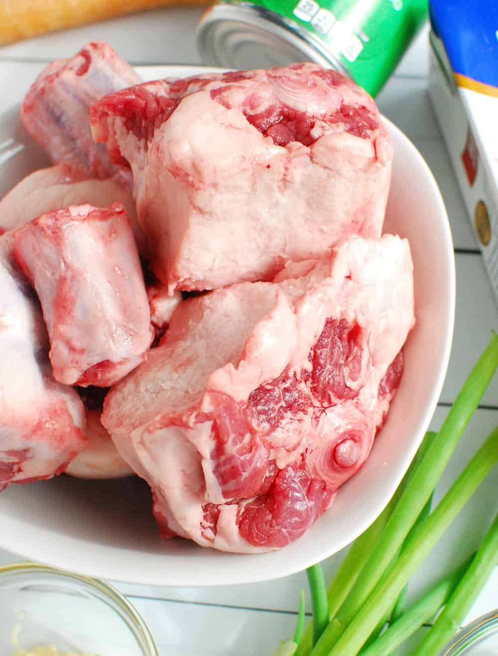 A white bowl with raw oxtails.