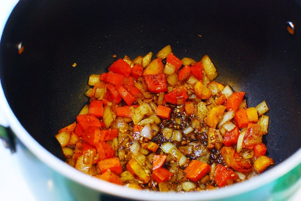 A pot with veggies and spices cooking.