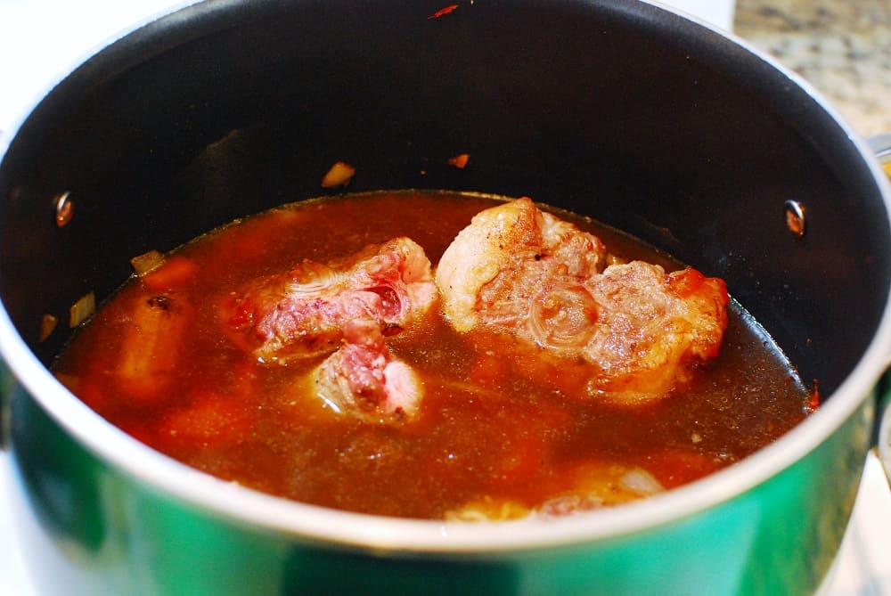 Braised oxtail in a pot at the start of cooking.