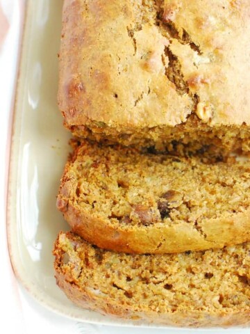 A loaf of pistachio banana bread next to some shelled pistachios.