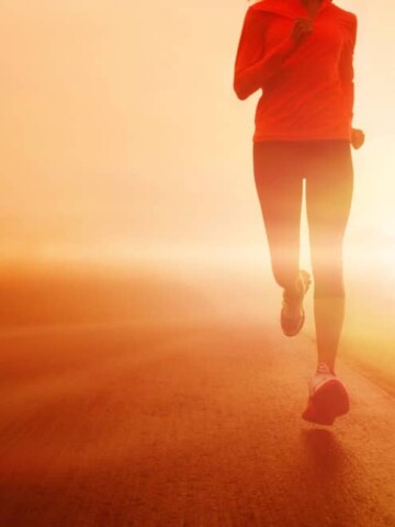 A woman running outside on the road at sunrise.