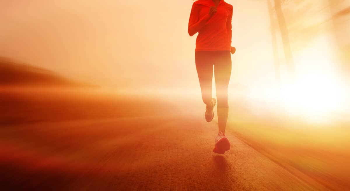 A woman running outside on the road at sunrise.
