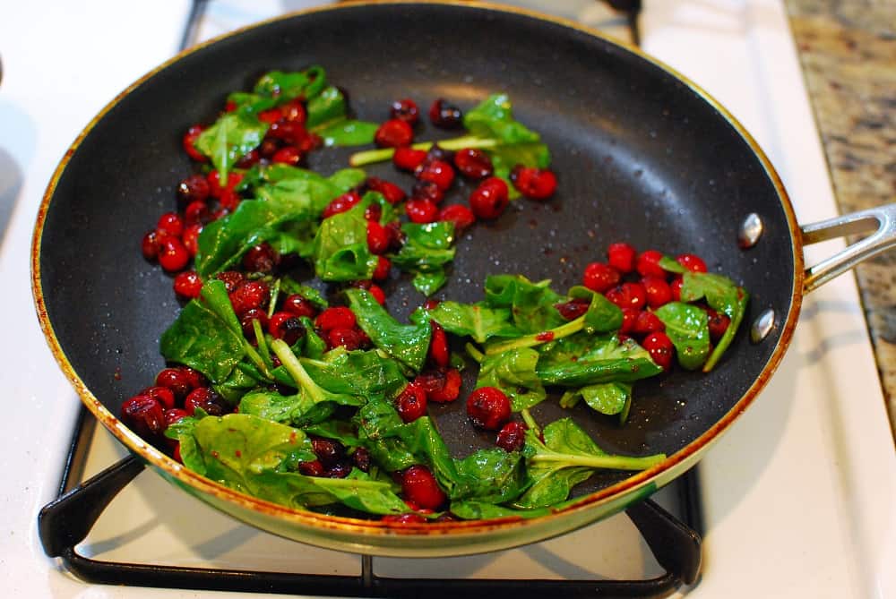 Cranberries and spinach in a sauté pan.