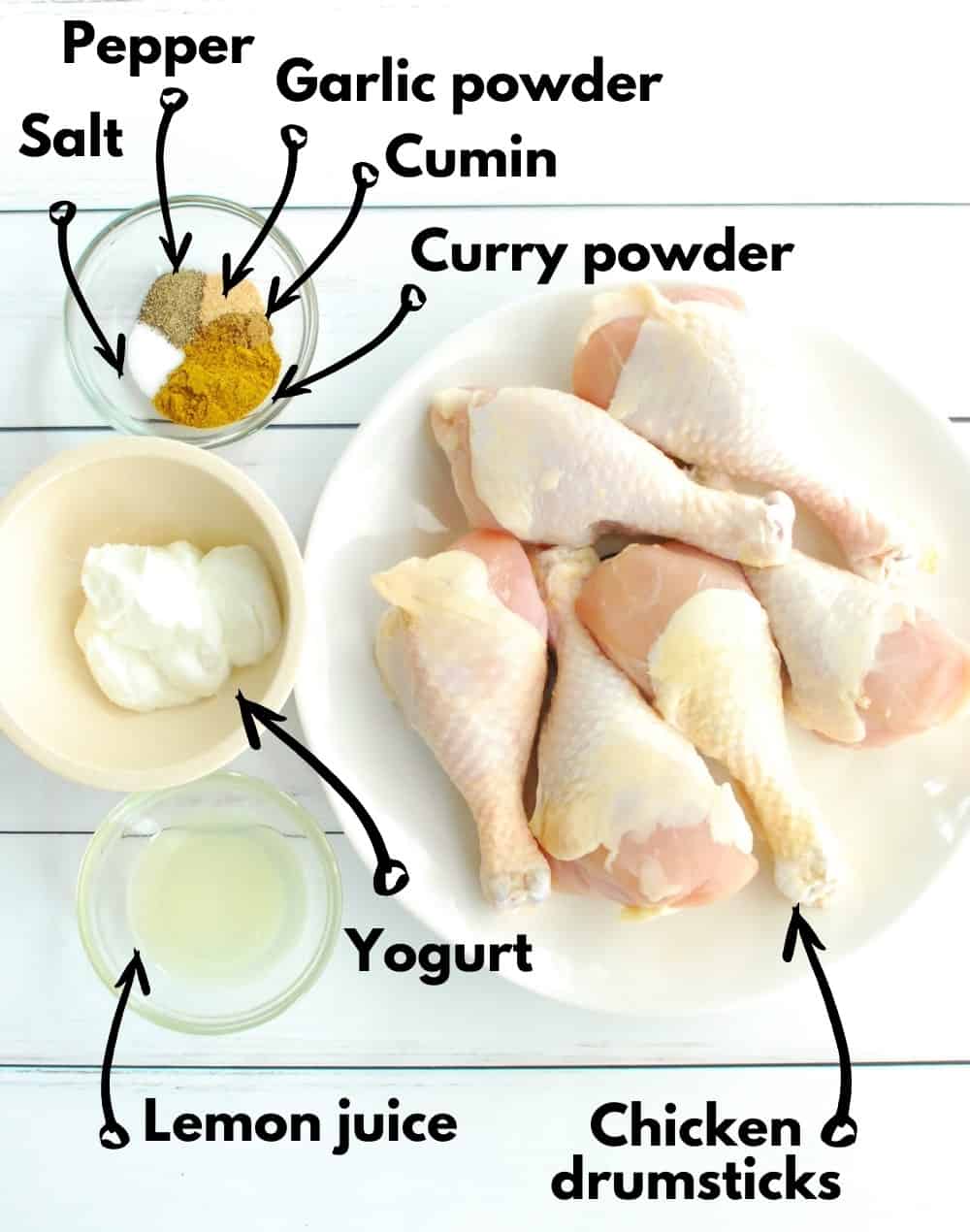 Overhead shot of chicken drumsticks, lemon juice, yogurt, and spice blend.