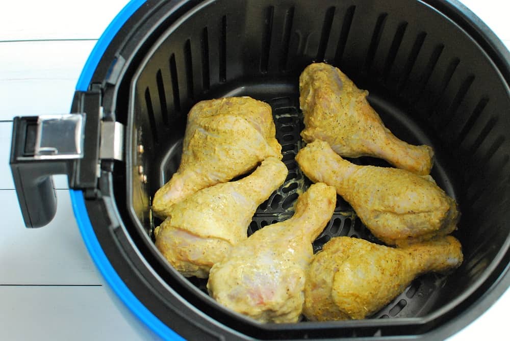 Chicken drumsticks in an air fryer basket before cooking