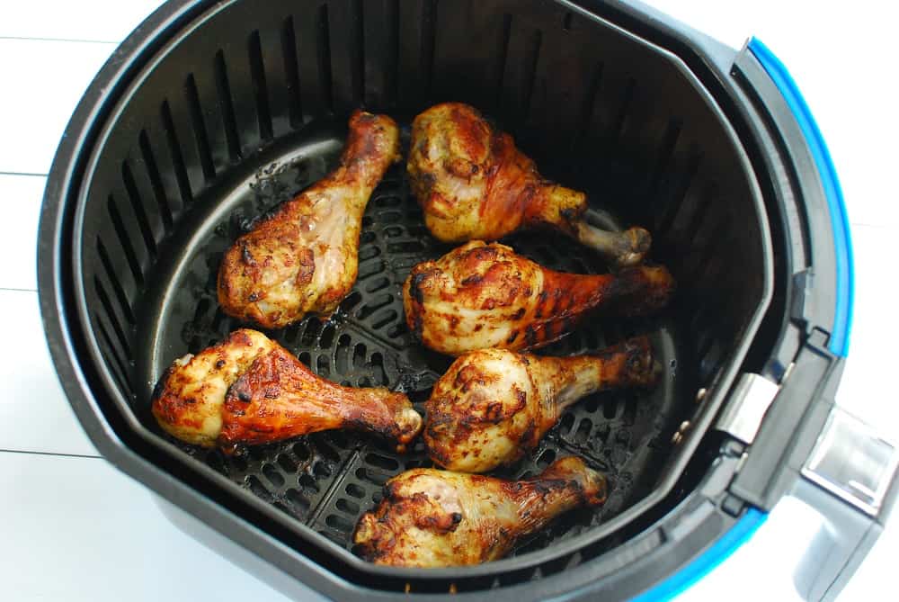 Chicken drumsticks in an air fryer basket after cooking.