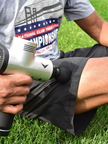 A man using a massager on his quads for triathlon training recovery.