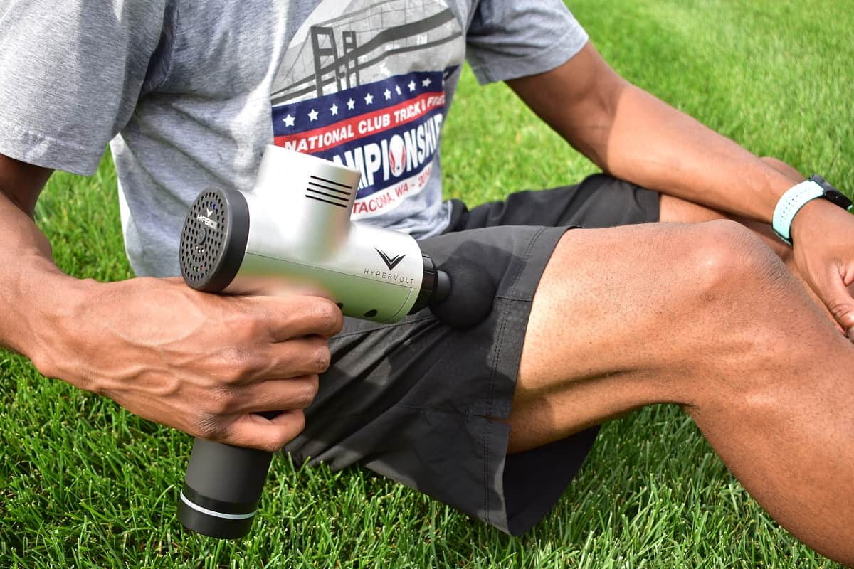 A man using a massager on his quads for triathlon training recovery.