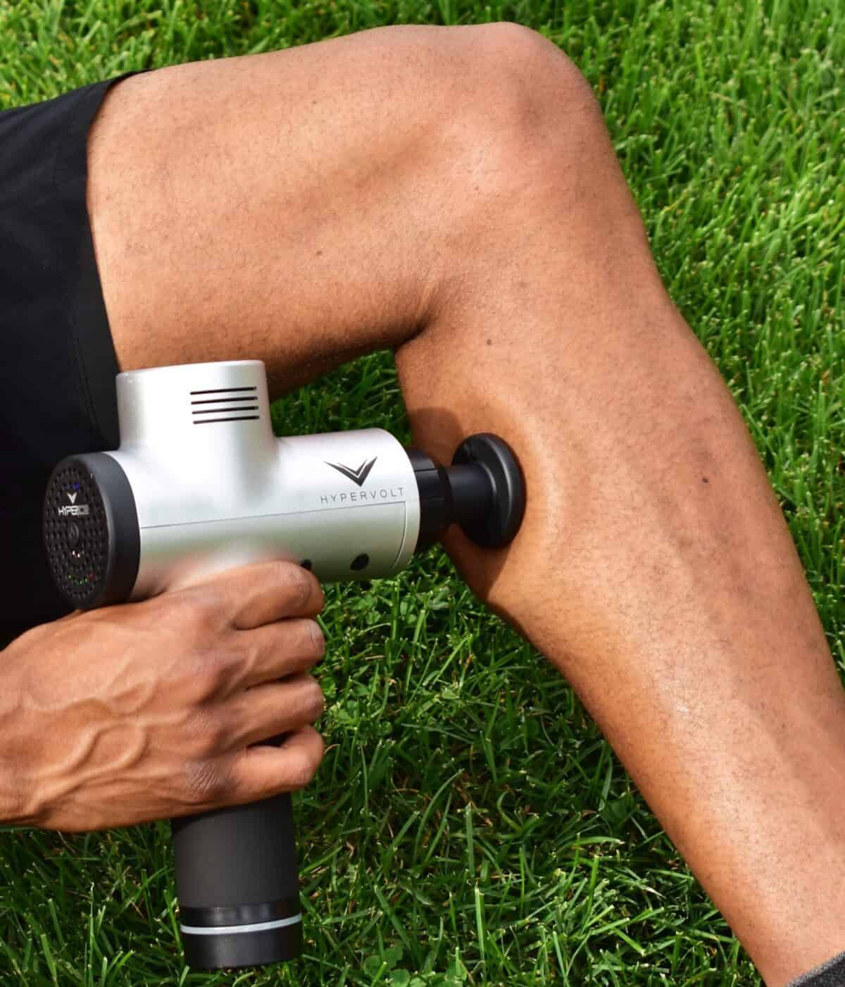 A man using a percussion massager on his calf.