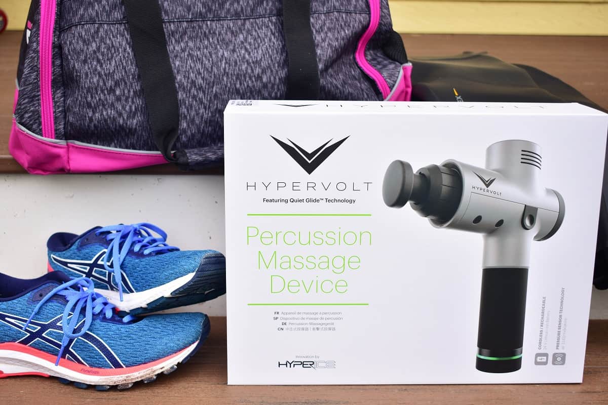 The Hypervolt massager in a box, next to sneakers and a gym bag.