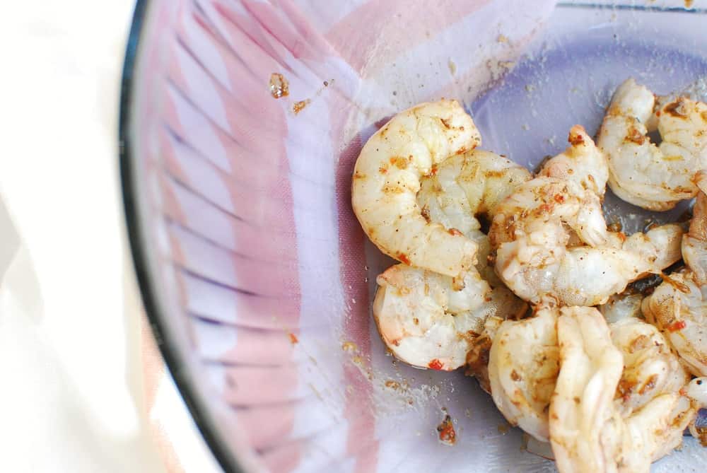 Shrimp after it was tossed in jerk seasoning paste in a bowl.