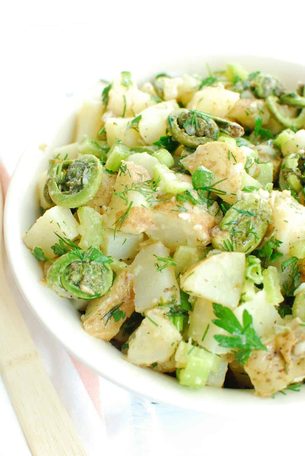 Close up of vegan dill potato salad with fiddleheads in a bowl.