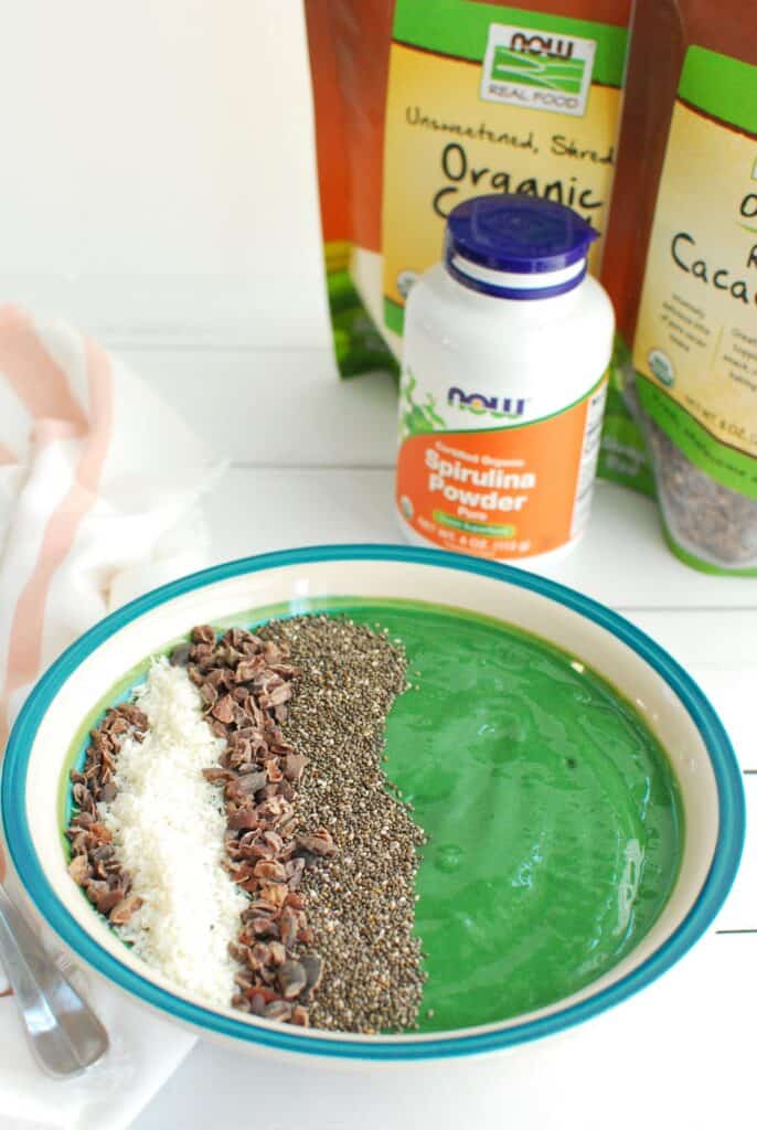 A spirulina smoothie bowl next to a bottle of spirulina.