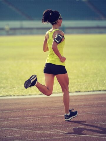 A woman running on a track in late afternoon.