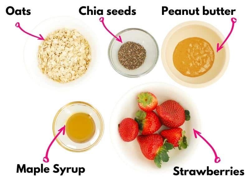 Oats, chia seeds, peanut butter, maple syrup, and strawberries on a table.