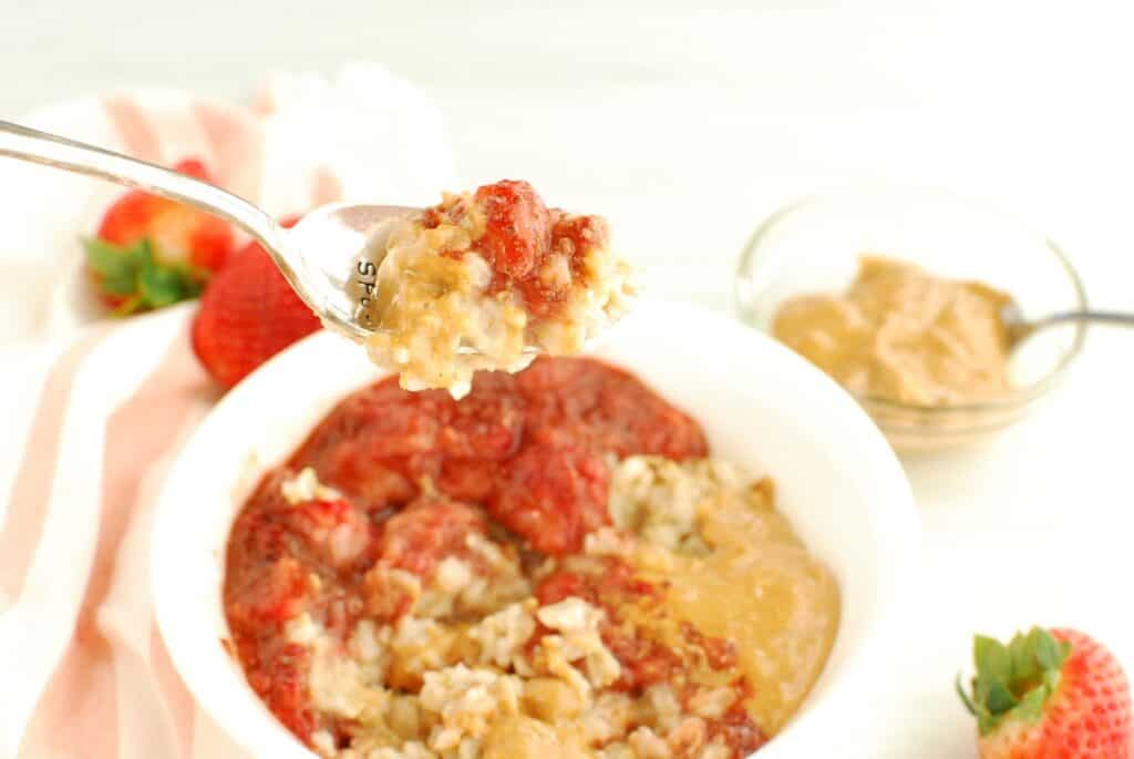 A spoon with a scoop of peanut butter and jelly oatmeal on it.