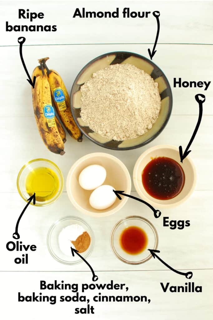 A bowl of almond flour, overripe bananas, eggs, olive oil, honey, vanilla, baking soda, baking powder, salt, and cinnamon.