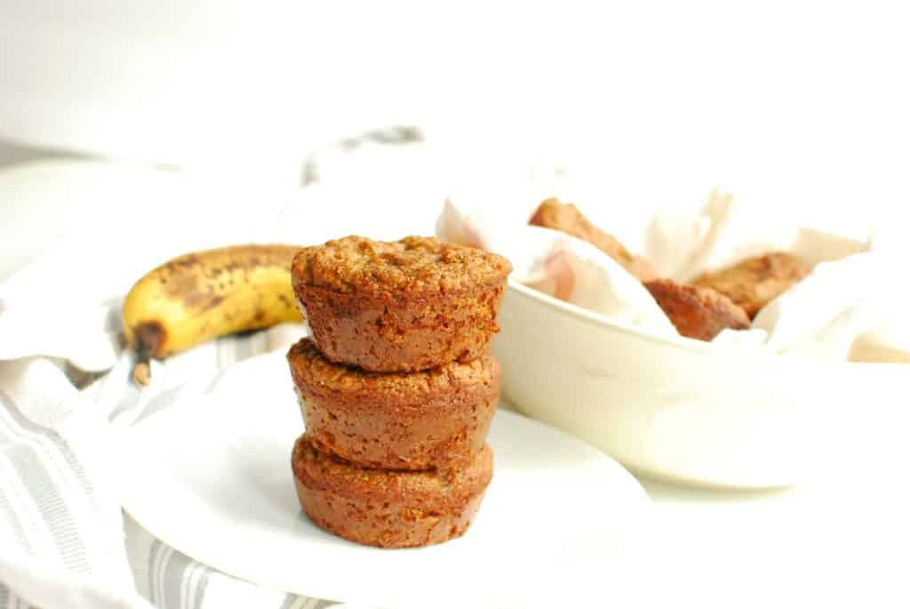 Three almond flour banana muffins stacked on a plate.
