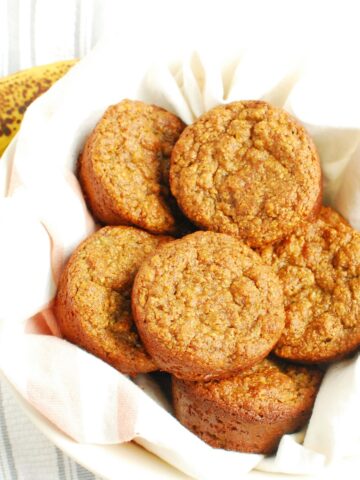 A bowl lined with a napkin filled with almond flour banana muffins.