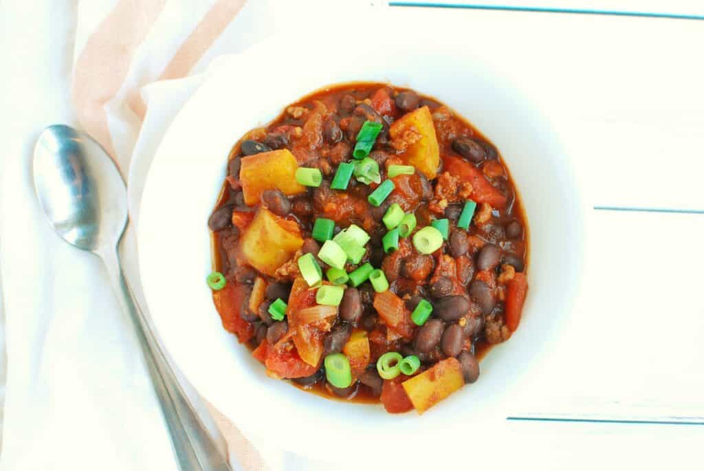 A bowl of chipotle chili next to a spoon.