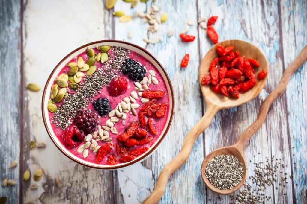 A smoothie bowl topped with goji berries, pumpkin seeds, chia seeds, and berries.