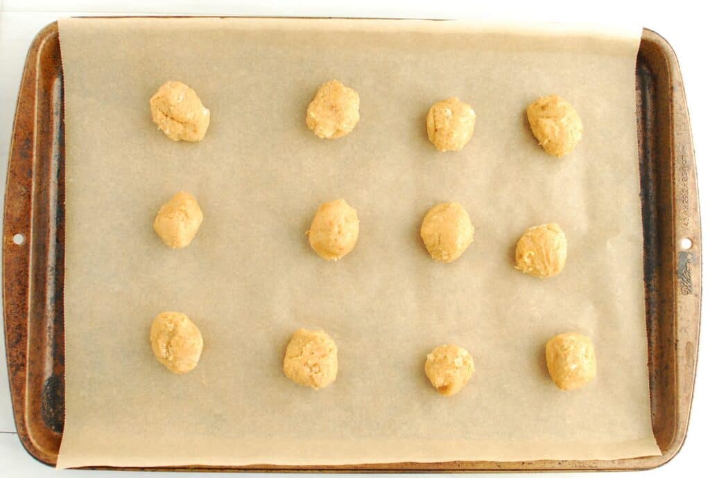 Balls of peanut butter cookie dough on a baking sheet.
