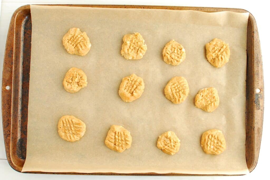 Unbaked cookies with fork gridlines pressed into them.