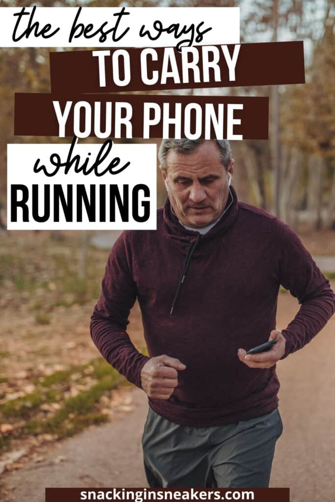 A man running outside in the fall carrying his phone in his hand.