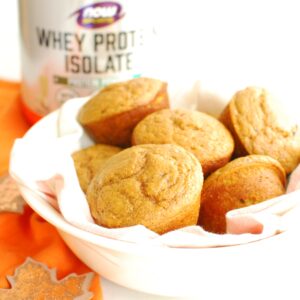 A bowl filled with pumpkin protein muffins, next to an orange napkin.