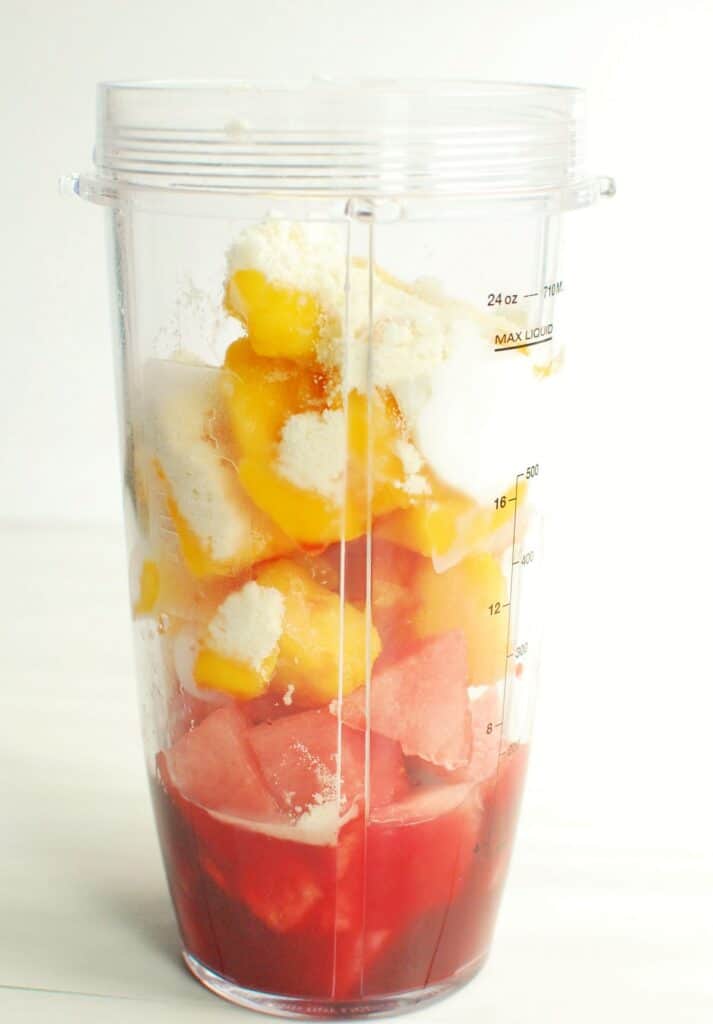 A blender cup full of watermelon, mango, greek yogurt, honey, tart cherry juice, and protein powder.