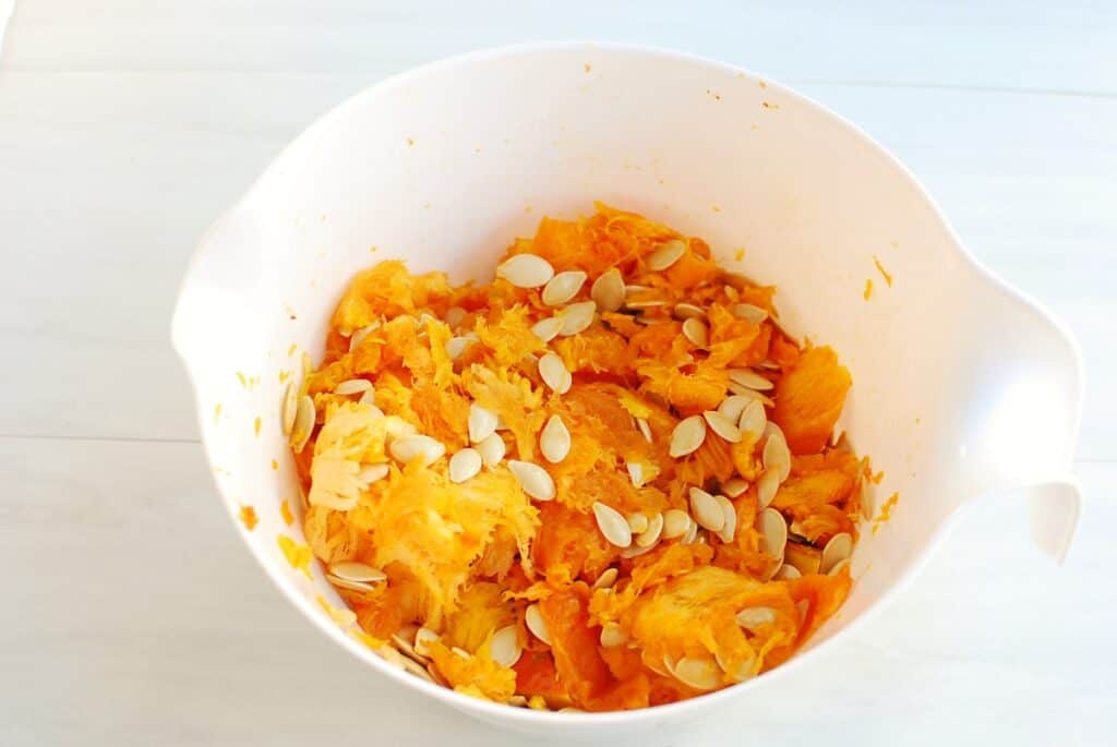 A bowl of stringy stuff and seeds from the inside of a pumpkin.