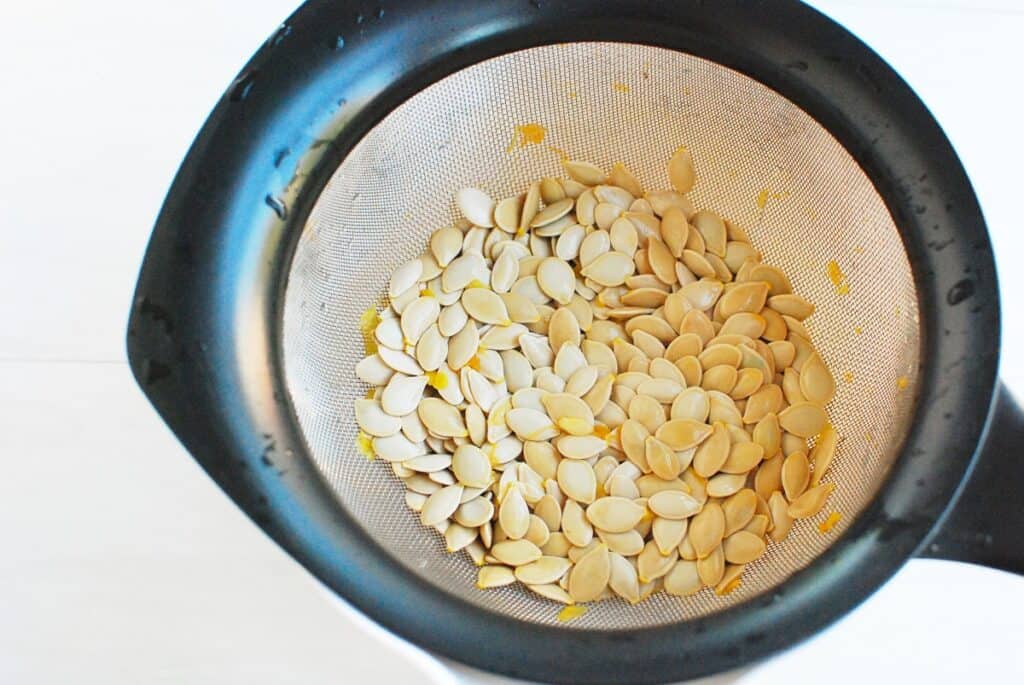 A strainer with pumpkin seeds in it.