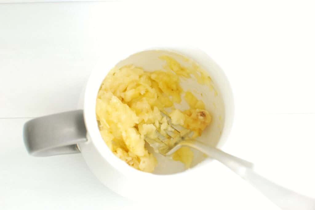 A mug with mashed banana in it.