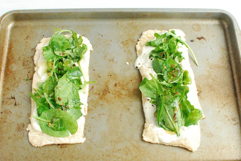 Pizzas on a baking sheet before being cooked.