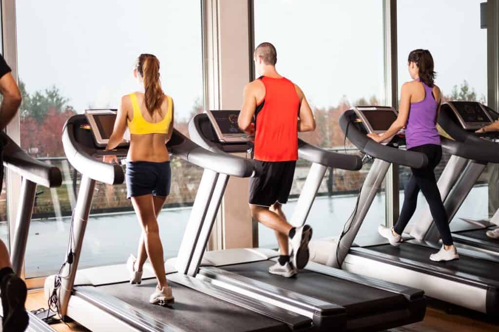 Several people doing walking or running workouts on treadmills.