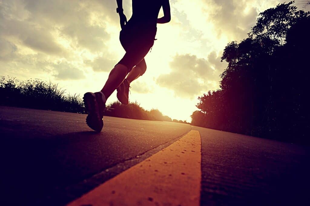 A runner on a flat road during late afternoon.