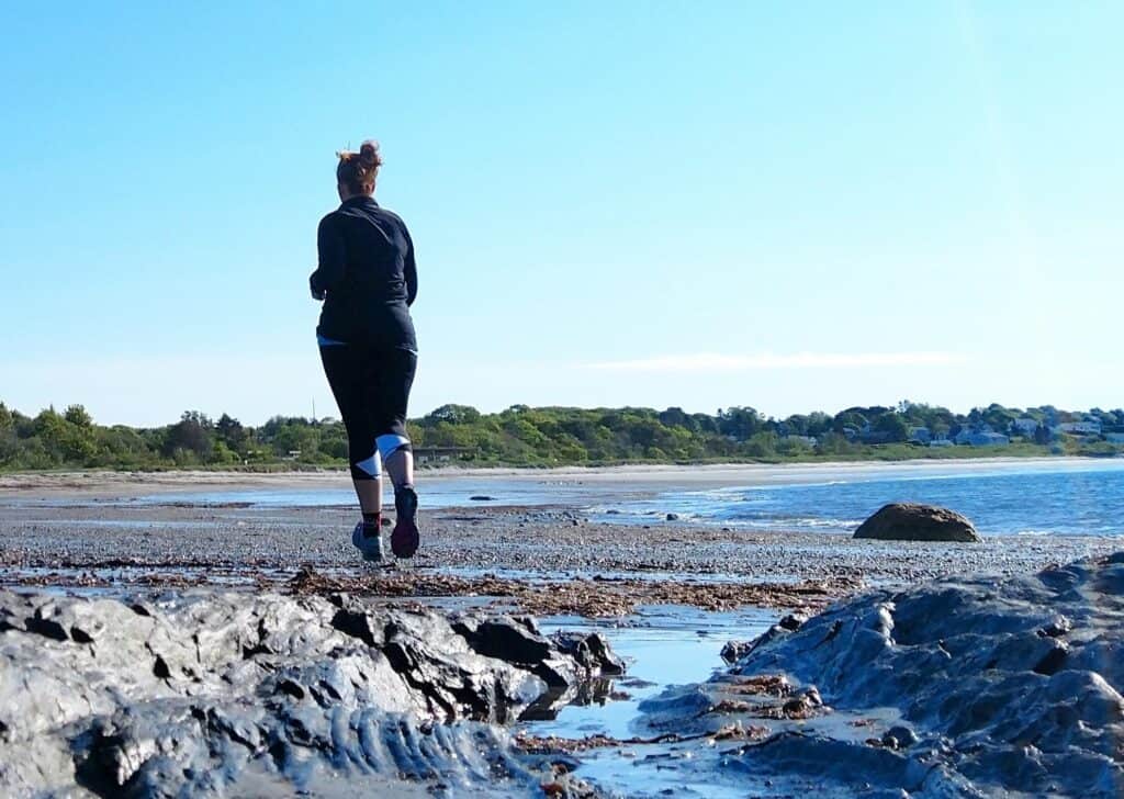 A woman running along the beach in Maine.