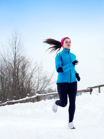 A woman running outside at Christmastime in the snow.